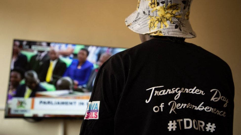 A Ugandan transgender woman who was recently attacked and currently being sheltered watches a TV screen showing the live broadcast of the session from the Parliament for the anti-gay bill, at a local charity supporting the LGBTQ Community near Kampala on March 21, 2023.