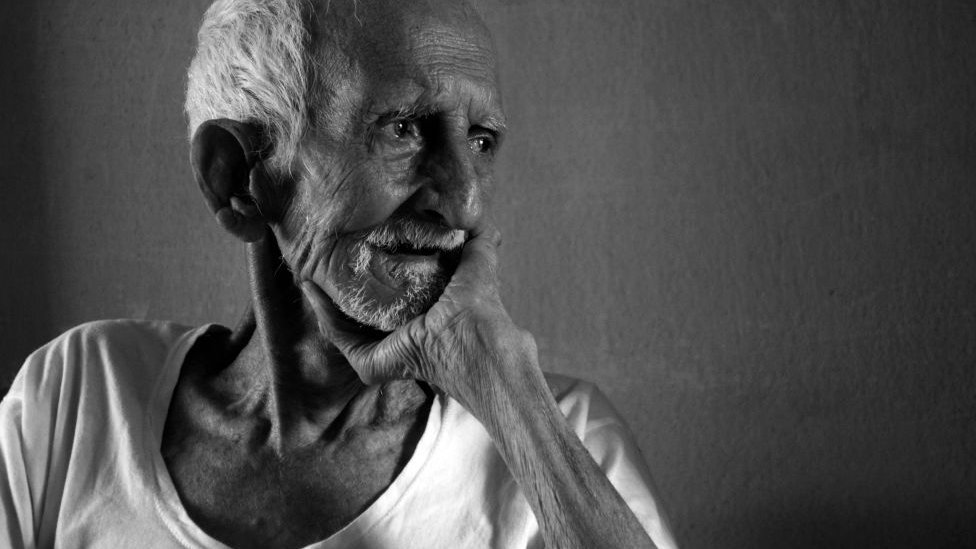 An old man looking outside with grief in the time of COVID-19 and hoping for those safe and pure days to come again, Nabagram, Hooghly, West Bengal, India.