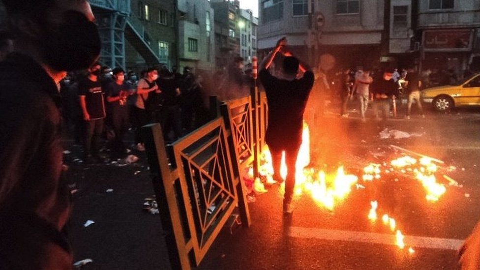 A road on fire with a protester dancing in the middle