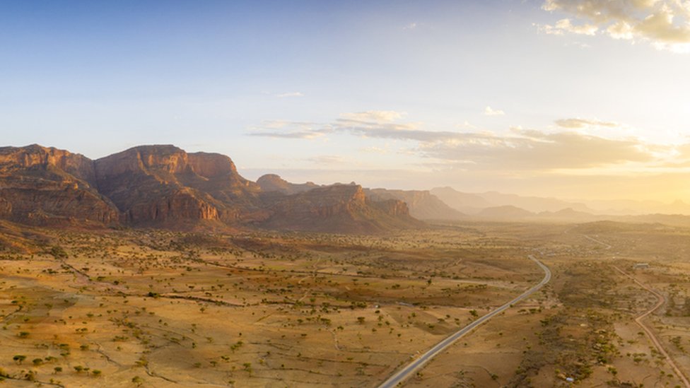 Sunset lit the empty road crossing the dry land of Gheralta Mountains, aerial view, Hawzen, Tigray Region, Ethiopia