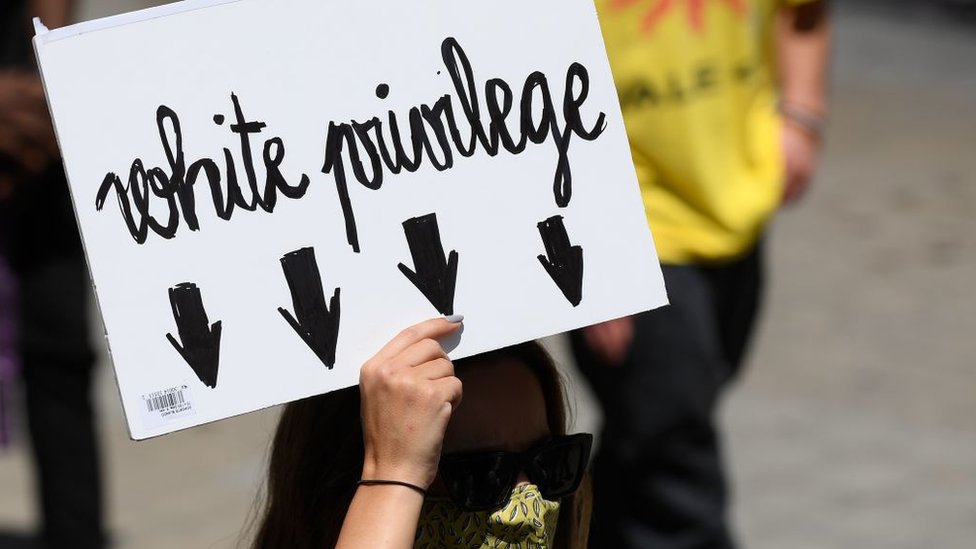Mujer con una pancarta que critica el privilegio blanco en Barcelona.