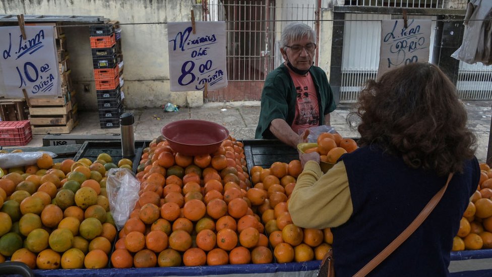 Mulher comprando frutas em feira livre