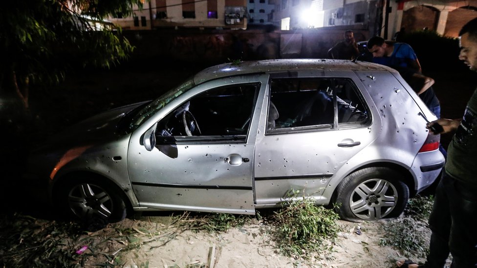 Палестинцы осматривают автомобиль, поврежденный в результате взрыва бомбы в городе Газа 27 августа 2019 г.