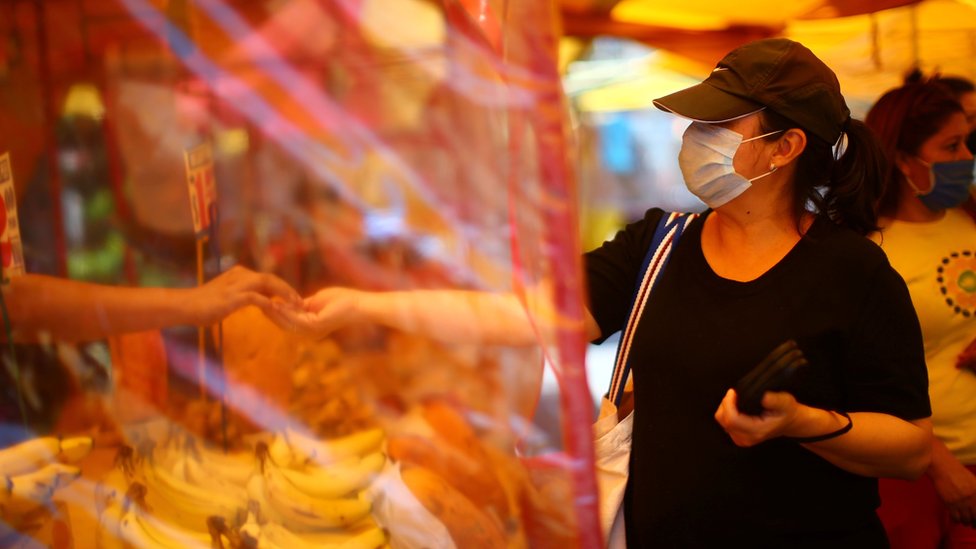 Женщина покупает на местном рынке, который вновь открывается в Мехико