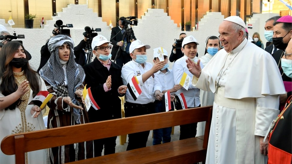 Pope Francis greets people as he arrives to hold a Mass at the Chaldean Cathedral of 