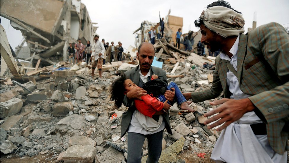 A girl is carried following an airstrike in Yemen in August 2017