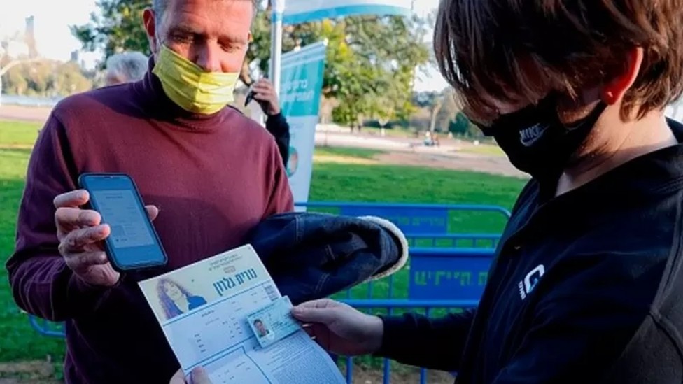 Hombre mostrando a una funcionaria su pasaporte de vacunación