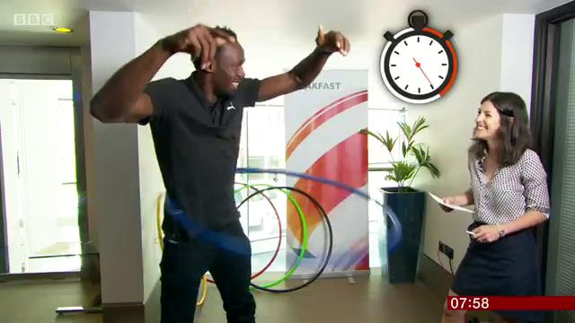 Usain Bolt talking to BBC Breakfast presenter while hula hooping