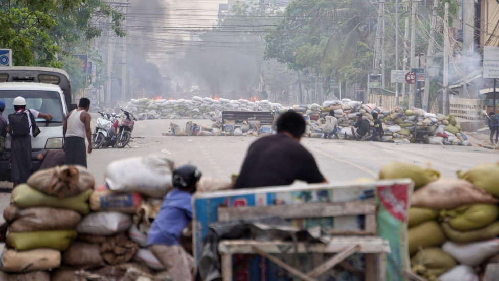 Protesters take cover behind barricades during a demonstration against the military coup in Mandalay, Myanmar March 21, 2021.