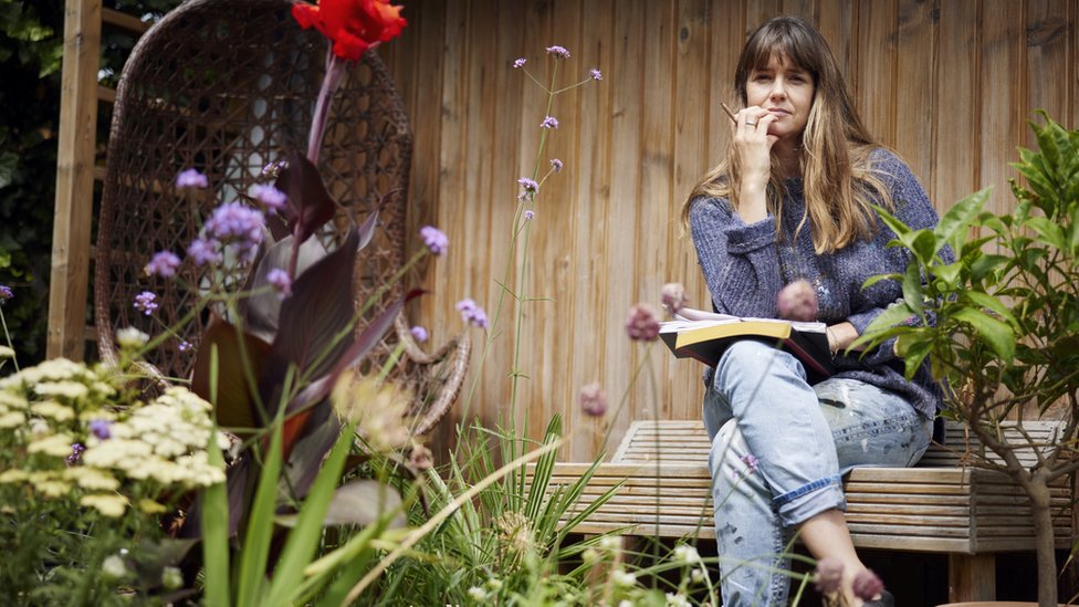 Una mujer sentada con las piernas cruzadas en jardín