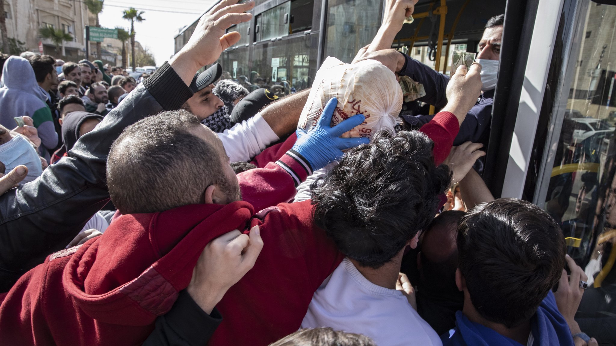Люди пытаются собрать хлеб из городских автобусов в Аммане, Иордания (24 марта 2020 г.)