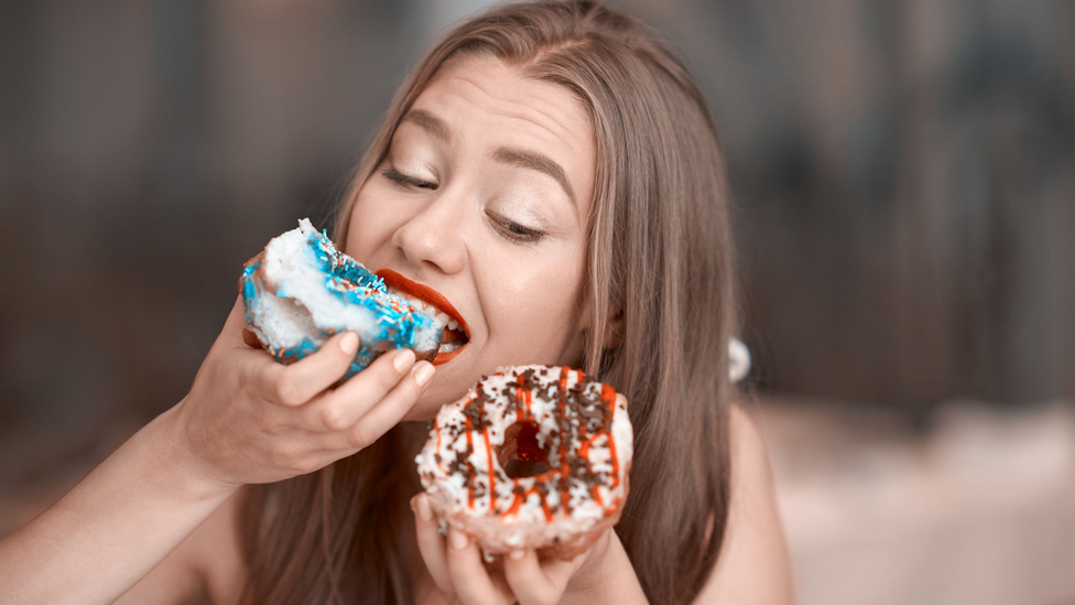 A woman bingeing on doughnuts