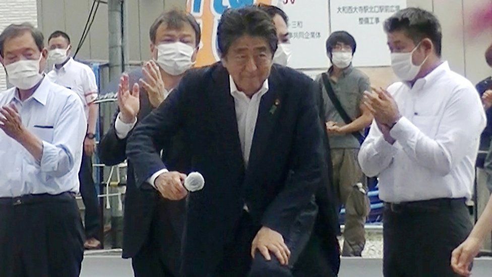 En una fotografía tomada momentos antes del ataque, se puede ver al presunto pistolero parado detrás de Abe con una camiseta gris y una bolsa negra.