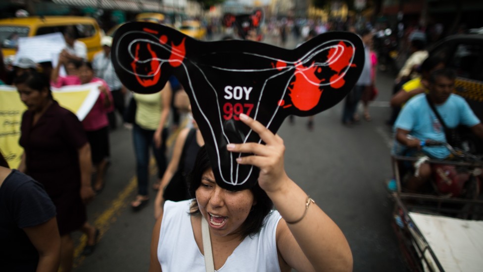 Mujer protestanto con un cartel en forma de útero