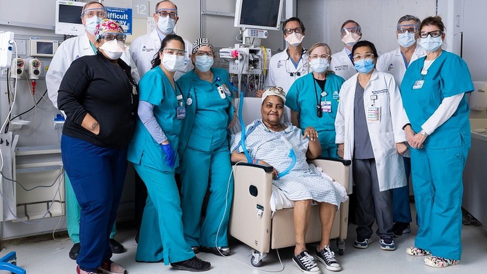 Paciente sentada e rodeada da equipe médica em ambiente hospitalar