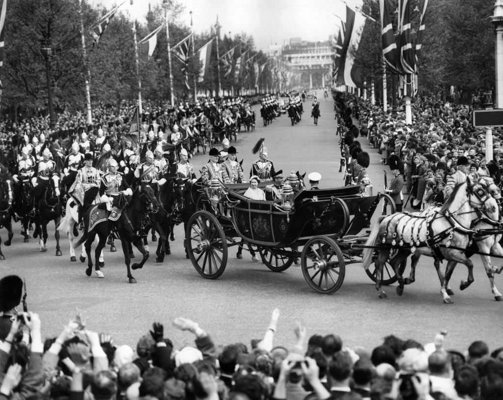 Londinenses llenan las calles para animar al sha de Irán, Mohamed Reza Pahlaví, llegando al Palacio de Buckingham con la reina Isabel y el duque de Edimburgo en un carruaje abierto el 5 de mayo de 1959 en Londres.