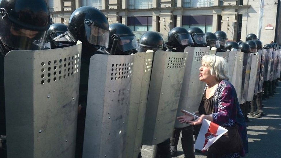 A woman protester faces off against riot police