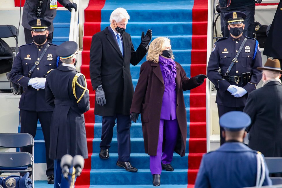 Bill Clinton and Hillary Clinton walk down steps together to find their seat