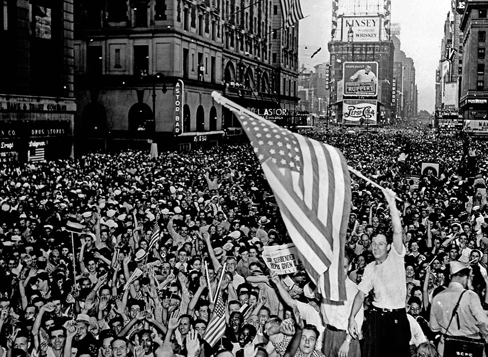 Толпа аплодирует мужчине, размахивающему американским флагом
