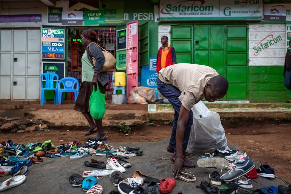Мужчина собирает обувь на рынке