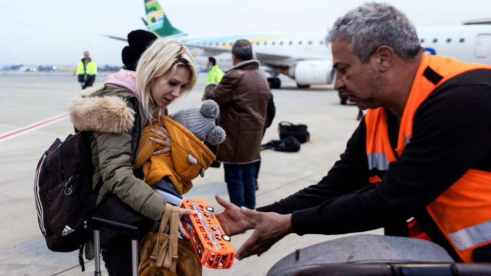 An Israeli man helps a Ukrainian refugee as she arrives on a flight from Romania at Tel Aviv's Ben Gurion airport (8 March 2022)
