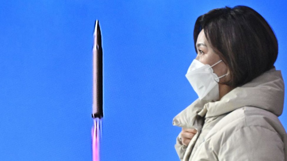 Una mujer con mascarilla en Seúl pasa frente a una pantalla que muestra la prueba de lanzamiento de un misil de Corea del Norte