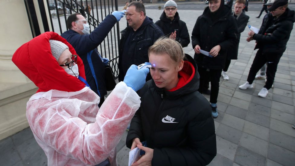 Aficionados tomándose la temperatura antes de entrar a un estadio de fútbol en Bielorrusia.