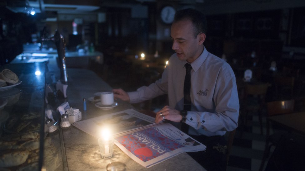 A man reads a newspaper by candlelight during the blackout in Argentina