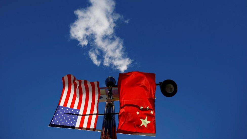 Flags of the United States and China fly from a lamppost