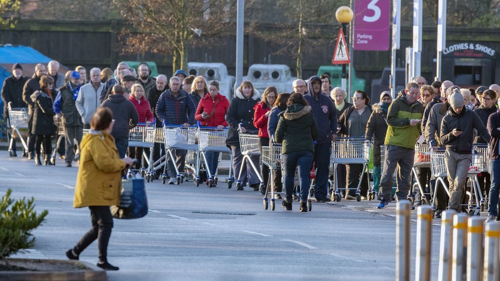 Покупатели выстраиваются в очередь перед супермаркетом Tesco в Ливерпуле, прежде чем он откроется