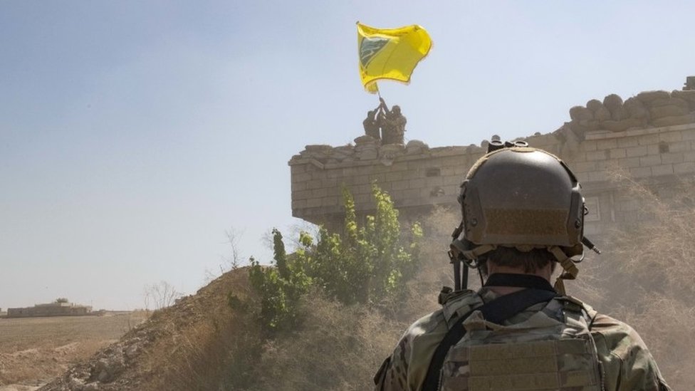 Американский солдат смотрит на солдаты группировки SDF, демонтирующие заставу YPG, сентябрь