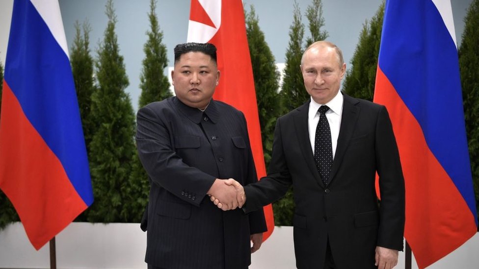 El líder de Corea del Norte, Kim Jong Un (izquierda) en un encuentro con el presidente de Rusia Vladimir Putin (derecha) in Vladivostok, Rusia en 2019 con banderas de ambos países al fondo.