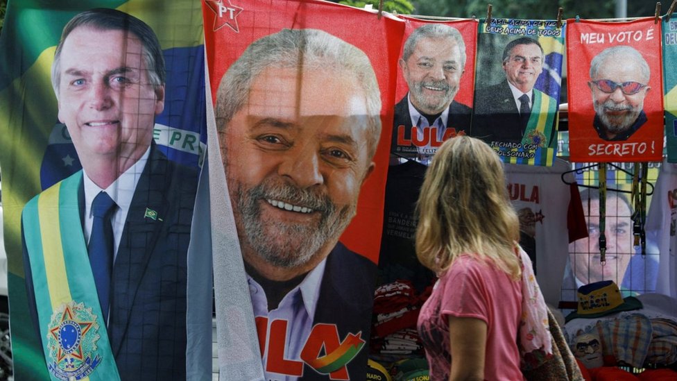 Una mujer mira material de campaña con las caras del candidato izquierdista Lula sa Silva y el presidente ultraderechista Jair Bolsonaro.
