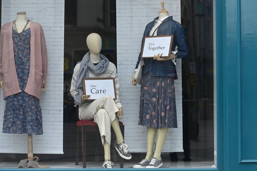 Манекены в магазине одежды в Белфасте с карточками с надписью «береги себя» и «держись вместе»