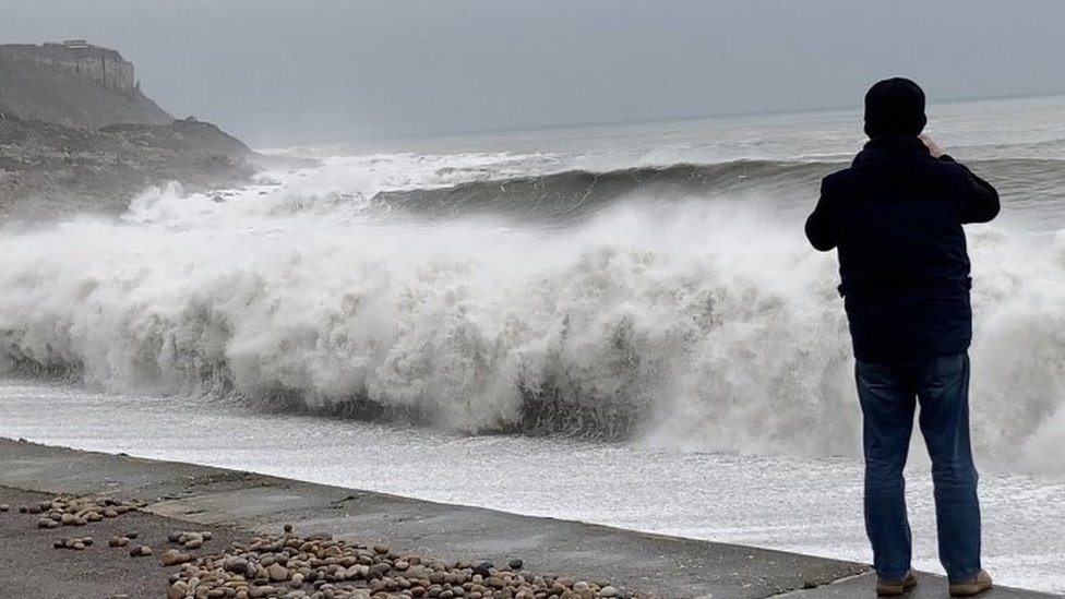 Looking west along Chesil beach from the Isle of Portland on a sunny day  with an onshore wind that has created some surf. Some anglers can be seen  fis Stock Photo 