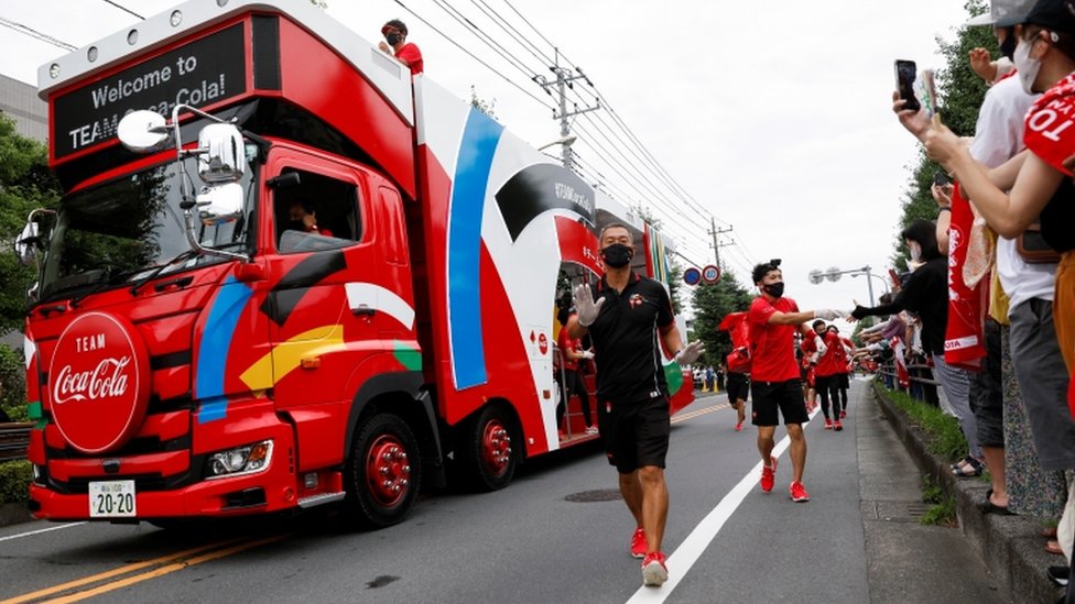 Sponsor truck and staff lead the relay before the runners" arrival during the first day of a Tokyo 2020 Olympic torch relay in the Saitama prefecture, amid the coronavirus disease (COVID-19) outbreak, in Wako, Japan July 6, 2021.