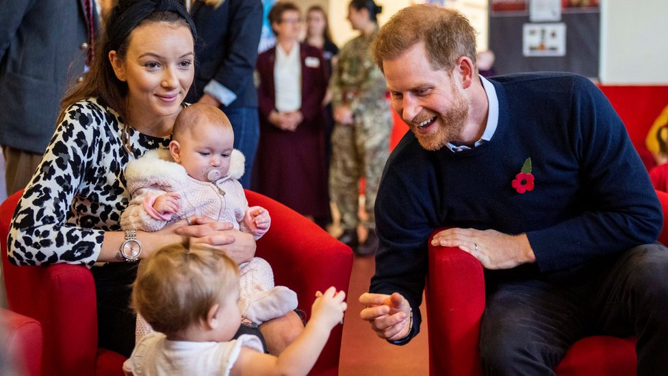 Prince Harry smiles at a toddler at Windsor's Broom Farm Community Centre