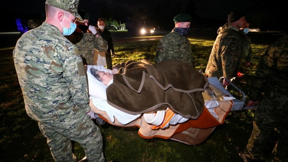 Military personnel carry an ill person on a stretcher to be evacuated to Zagreb by helicopter