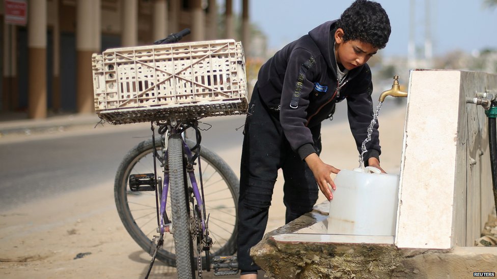 Un niño llena una garrafa de agua en una fuente