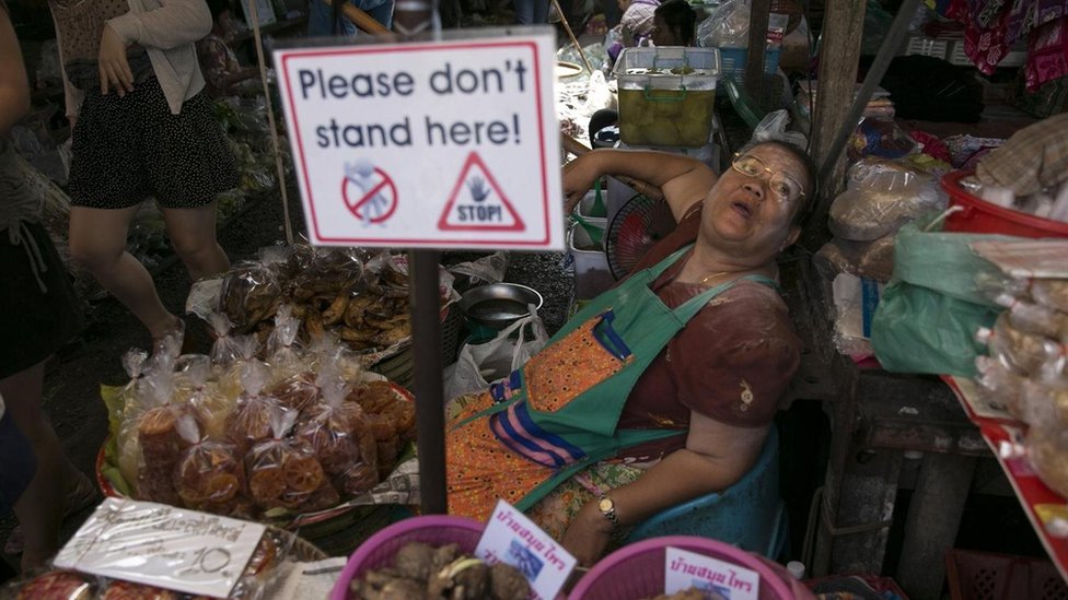 إحدى البائعات في سوق مايكلونغ بتايلاند محاطة بالسياح