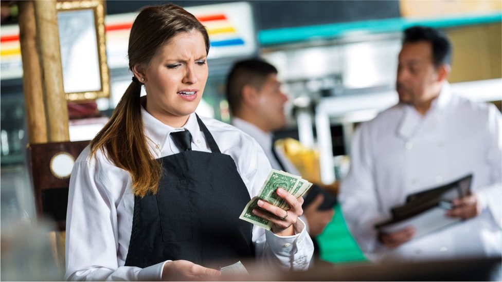 Atendente de restaurante recebendo notas de dinheiro