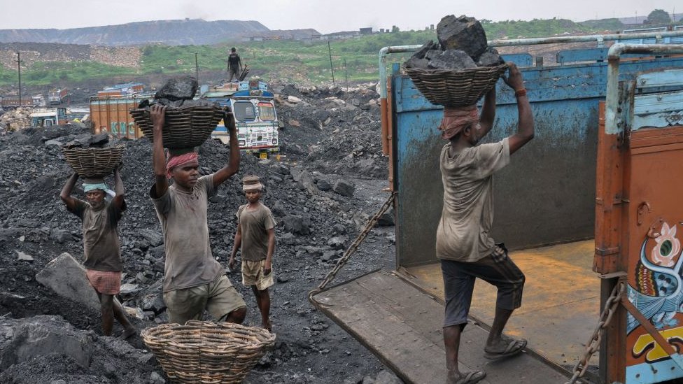 На этой фотографии, сделанной 7 декабря 2017 года, показаны индийские рабочие, загружающие уголь в грузовики на карьере в Дханбаде в восточно-индийском штате Джаркханд.