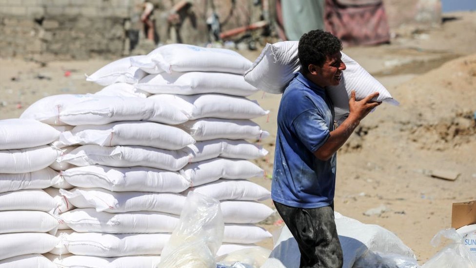 A Palestinian man carries a bag of flour provided as aid to families at the United Nations Relief and Works Agency for Palestine Refugees (UNRWA) distribution centre, in the Al-Shati refugee camp in Gaza city on 31 July 2023