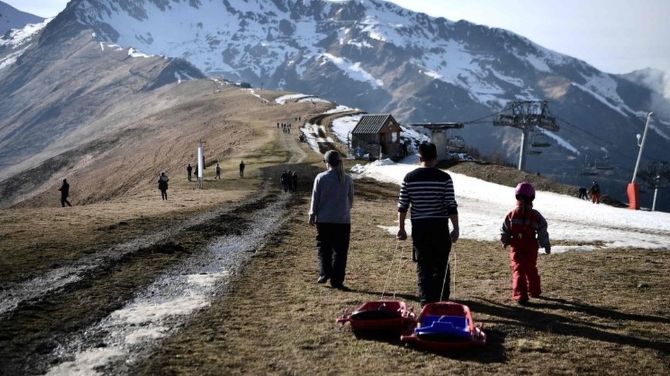 Люди тянут сани на вершине горнолыжного склона недалеко от Люшона во французских Пиренеях