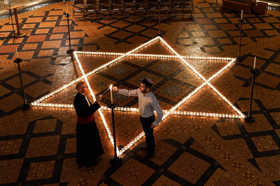Преподобный каноник доктор Кристофер Коллингвуд и Джошуа Дэниелс из еврейского общества Йоркского университета зажигают 600 свечей