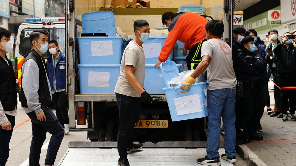 香港觀塘《立場新聞》辦公室所在大樓外警員把查抄證物搬上貨車（29/12/2021）