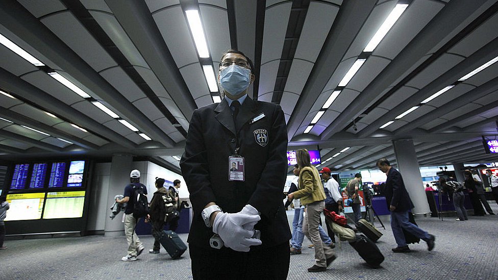 Медицинский работник готов попросить пассажиров снять головные уборы перед проверкой температуры 27 апреля 2009 года в международном аэропорту Гонконга