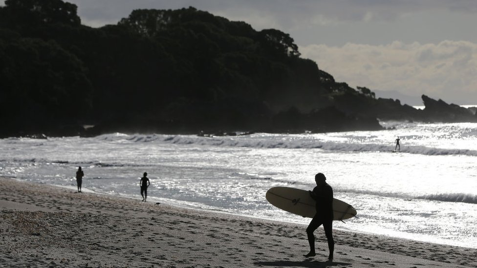 A surfer exists the water in Cambridge, New Zealand.