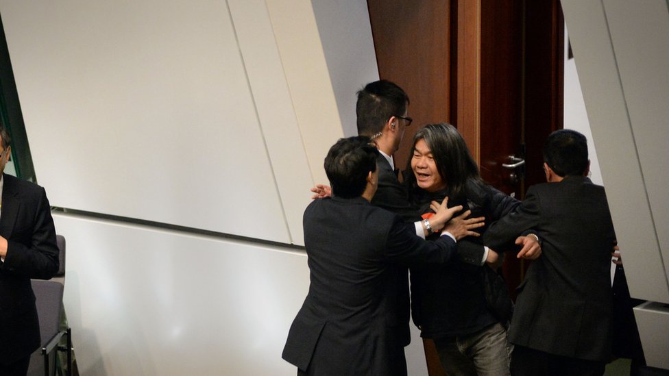 Леунг Квок-хун, известный как «Длинноволосый» (справа), исключен из палат Законодательного совета за то, что он вмешался во время выступления главы исполнительной власти Люн Чун-ин в 2016 году в Адмиралтейском районе Гонконга 13 января 2016 г.