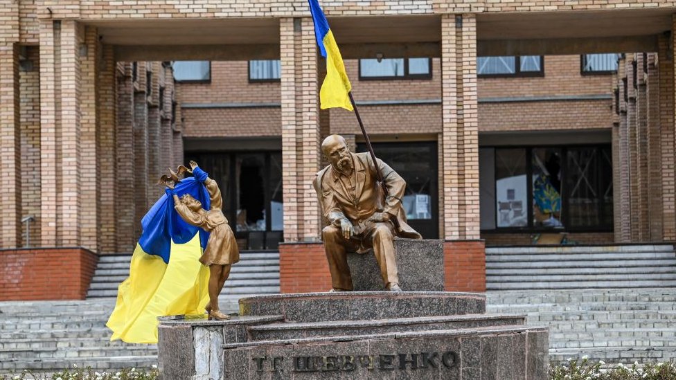 Imagen muestra estatuas cubiertas con banderas ucranianas.